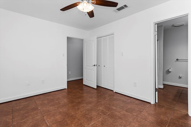 unfurnished bedroom with ceiling fan, a closet, and dark tile patterned flooring