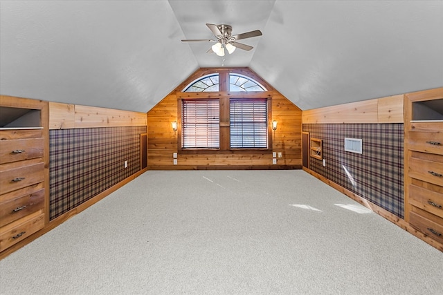 bonus room with wood walls, carpet floors, lofted ceiling, and ceiling fan