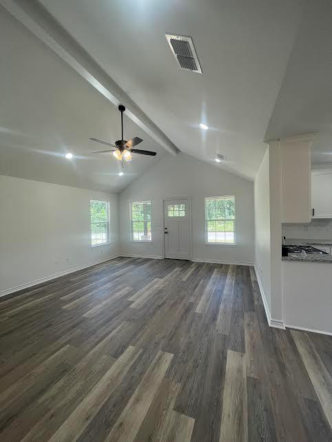 unfurnished living room featuring vaulted ceiling with beams, ceiling fan, and dark wood-type flooring