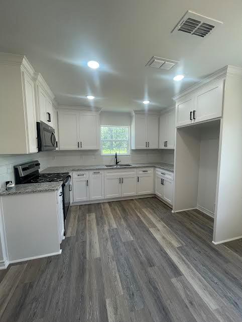 kitchen featuring white cabinets, sink, electric range, light stone countertops, and dark hardwood / wood-style flooring