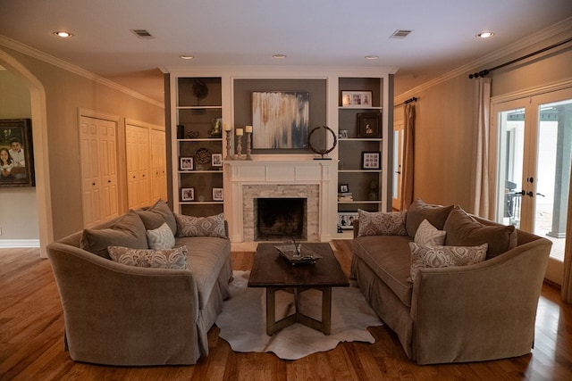 living room with built in features, crown molding, and hardwood / wood-style flooring