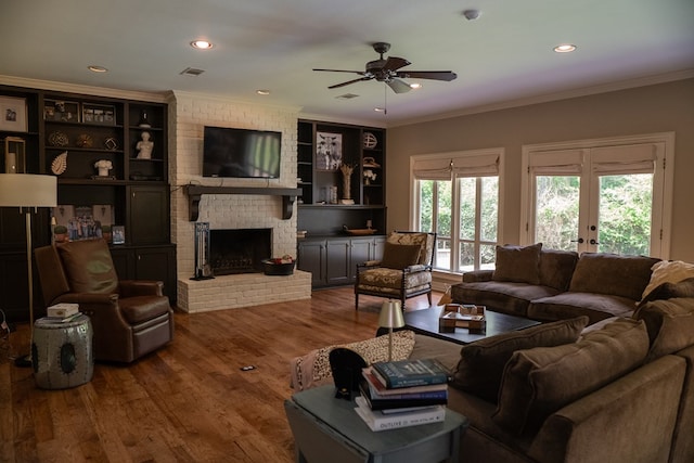 living room with a brick fireplace, crown molding, and wood-type flooring