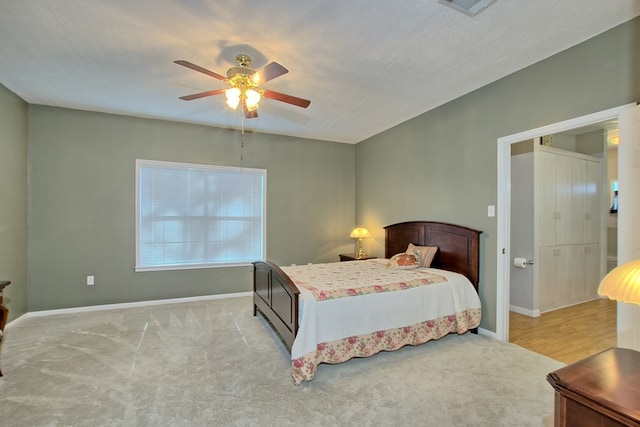 bedroom featuring light carpet, a textured ceiling, and ceiling fan