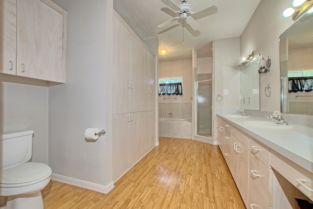 full bathroom featuring hardwood / wood-style floors, vanity, ceiling fan, separate shower and tub, and toilet