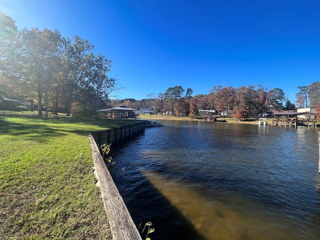 view of dock with a yard and a water view