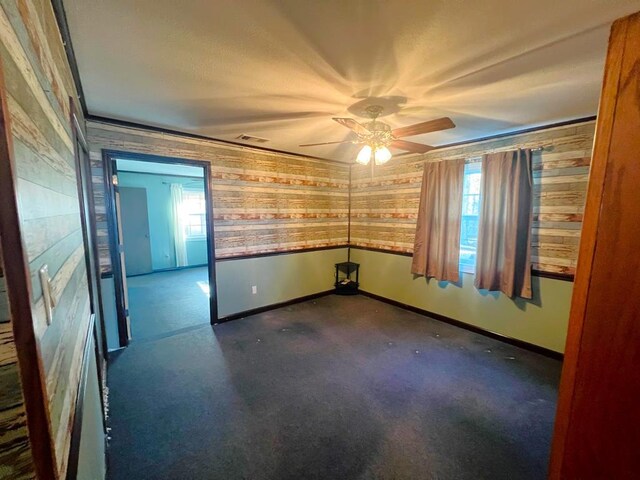 carpeted spare room featuring a wealth of natural light, baseboards, ceiling fan, and ornamental molding