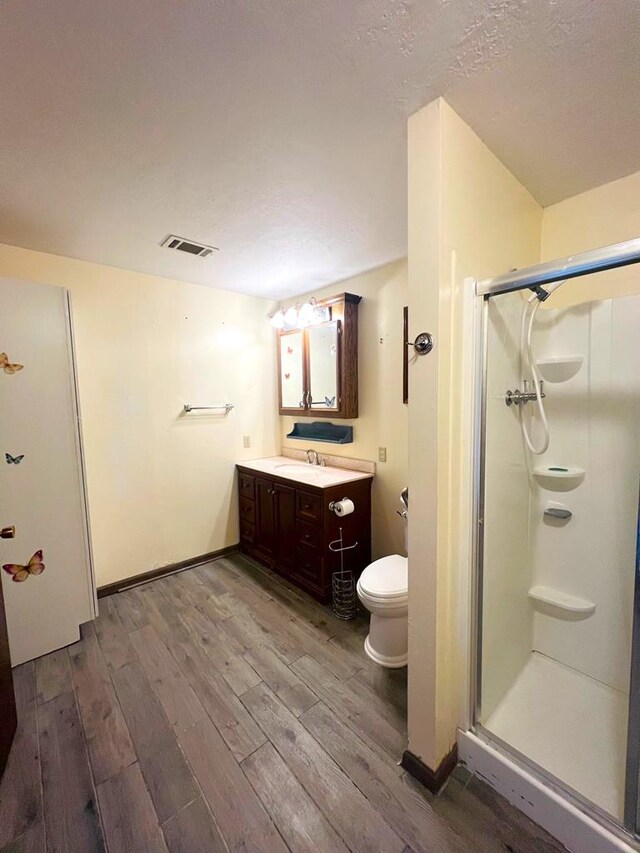 full bath with vanity, toilet, wood finished floors, and a shower stall