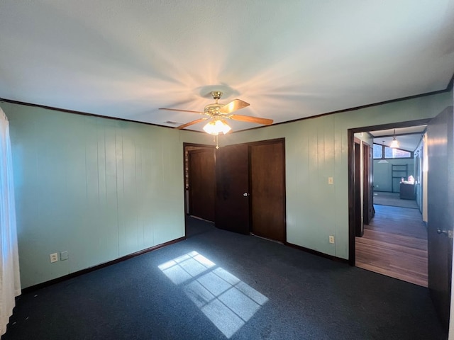 unfurnished bedroom featuring dark colored carpet, a closet, and ceiling fan