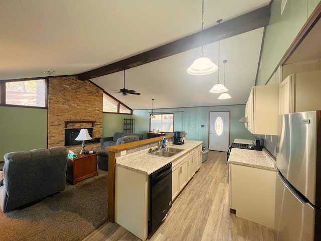 kitchen featuring a sink, a brick fireplace, vaulted ceiling with beams, appliances with stainless steel finishes, and a kitchen island with sink
