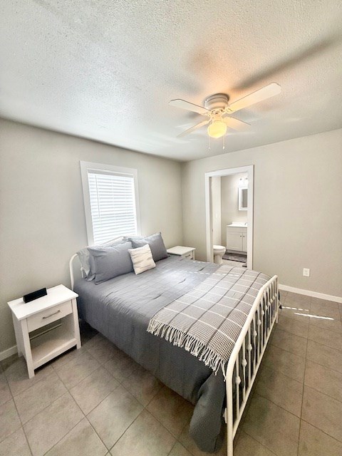 tiled bedroom with ceiling fan, connected bathroom, and a textured ceiling