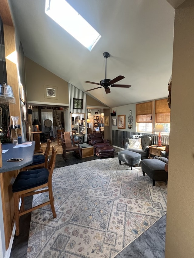 living room featuring a skylight, ceiling fan, and high vaulted ceiling