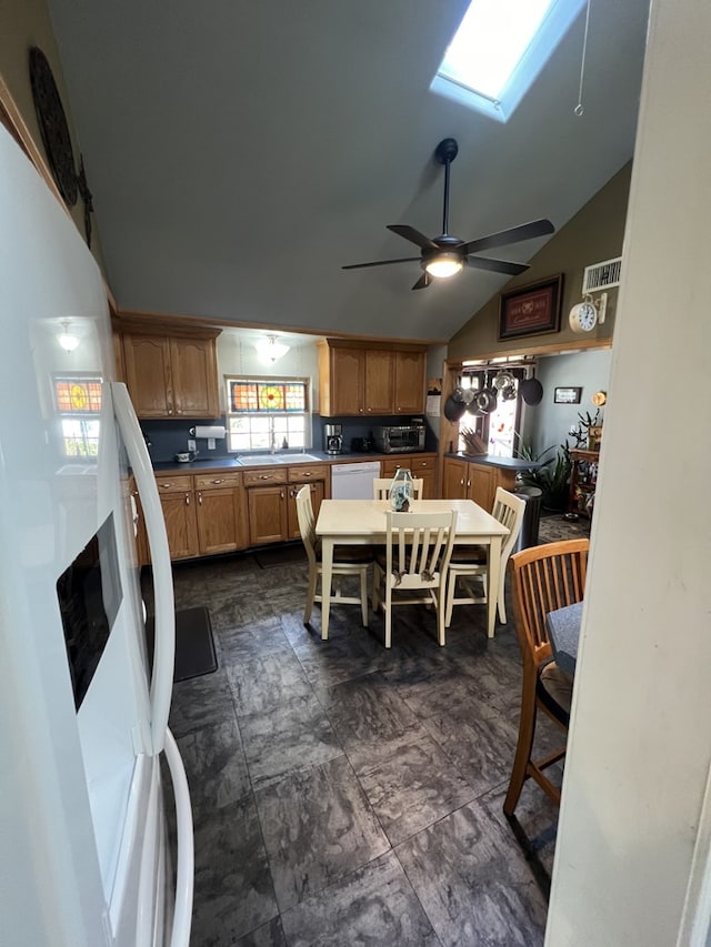 kitchen with lofted ceiling with skylight, sink, ceiling fan, and white appliances