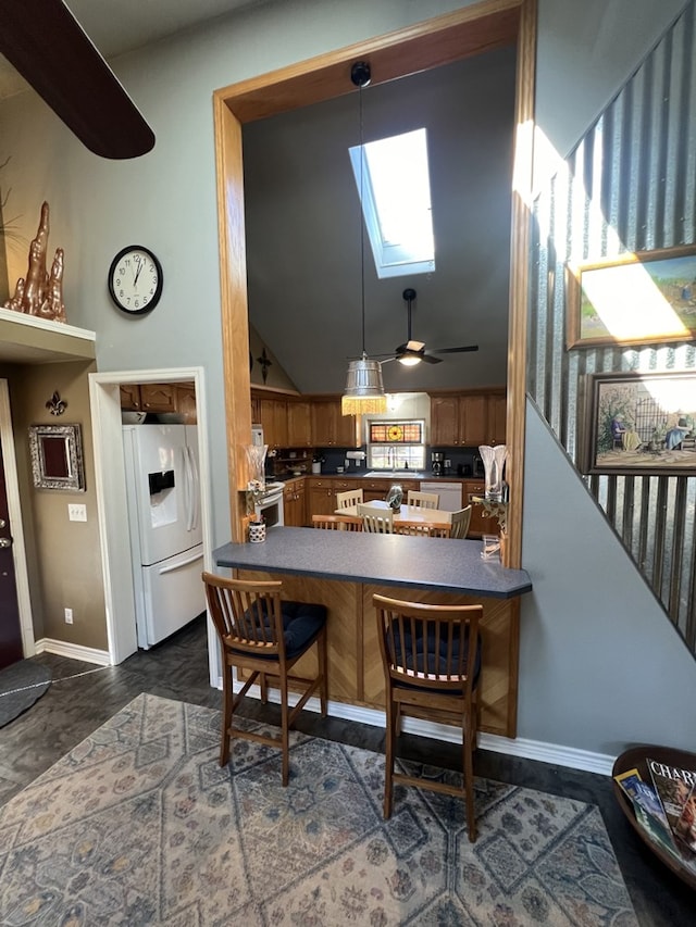 kitchen with ceiling fan, white fridge with ice dispenser, kitchen peninsula, lofted ceiling with skylight, and decorative light fixtures