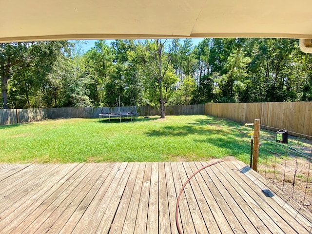 wooden terrace featuring a lawn and a trampoline