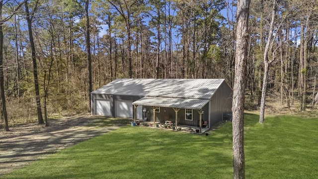 view of outbuilding featuring an outdoor structure, driveway, and a view of trees