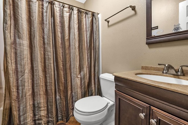 full bath with a textured wall, curtained shower, toilet, and vanity