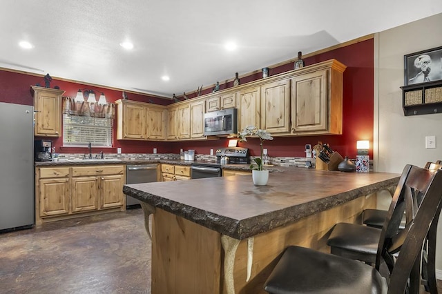 kitchen featuring dark countertops, a breakfast bar area, appliances with stainless steel finishes, and a peninsula