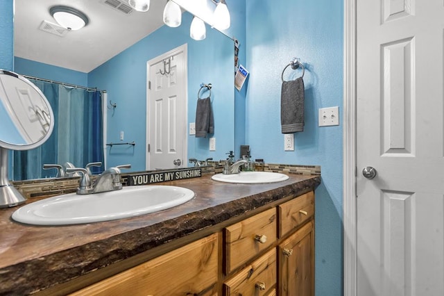 bathroom with double vanity, visible vents, and a sink