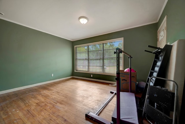 exercise area featuring wood-type flooring and ornamental molding