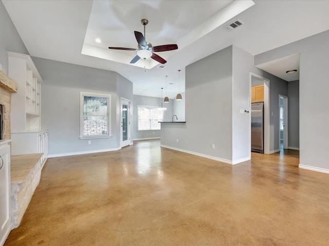 unfurnished living room with a tray ceiling and ceiling fan