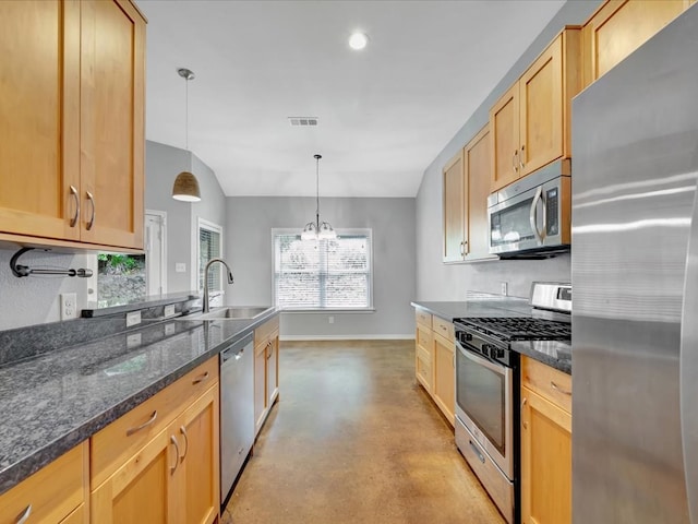 kitchen featuring sink, dark stone counters, pendant lighting, lofted ceiling, and appliances with stainless steel finishes