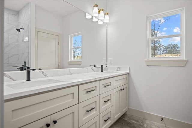 bathroom with a sink, baseboards, double vanity, and a tile shower