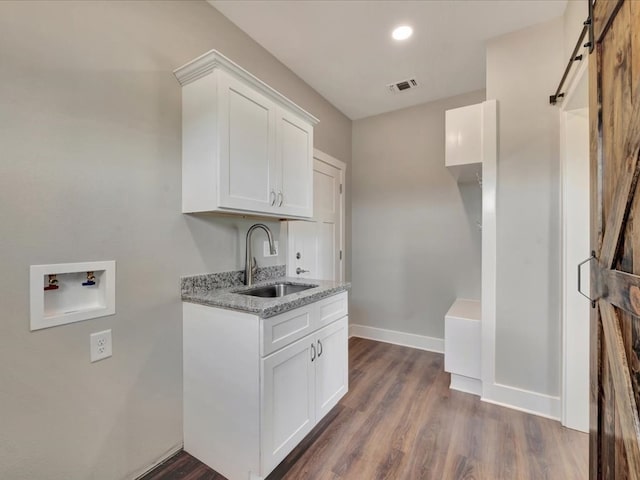 128 Stoney Rdg, Lufkin, TX 75904 - washroom featuring washer hookup, a barn door, dark wood-style floors, cabinet space, and recessed lighting