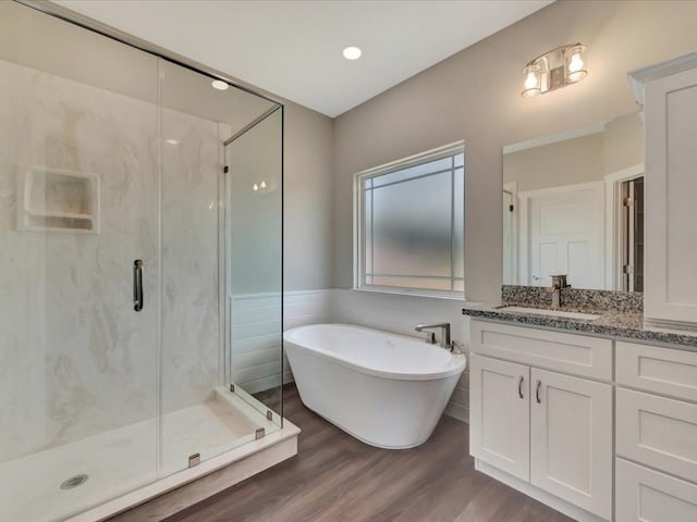 128 Stoney Rdg, Lufkin, TX 75904 - bathroom with a marble finish shower, vanity, a freestanding tub, wood finished floors, and wainscoting