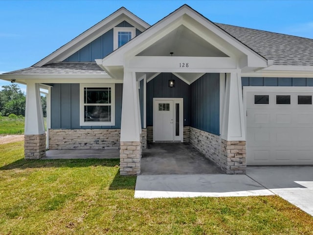 128 Stoney Rdg, Lufkin, TX 75904 - view of front of home with board and batten siding, roof with shingles, an attached garage, a front lawn, and stone siding