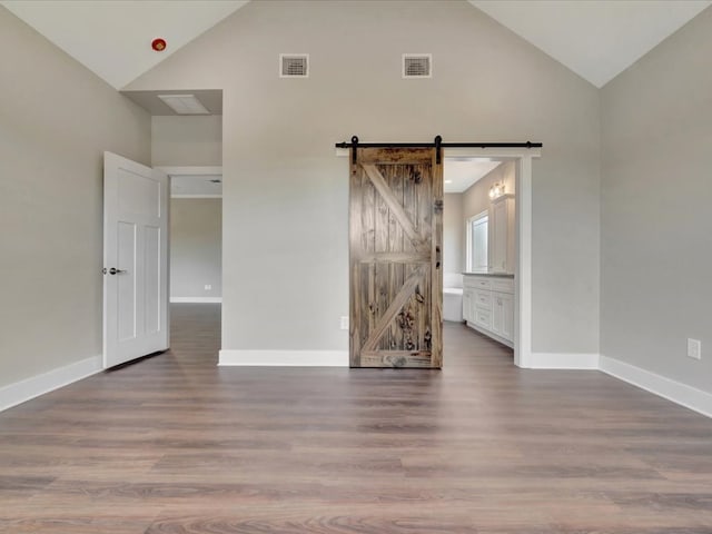 128 Stoney Rdg, Lufkin, TX 75904 - empty room featuring high vaulted ceiling, wood finished floors, and a barn door
