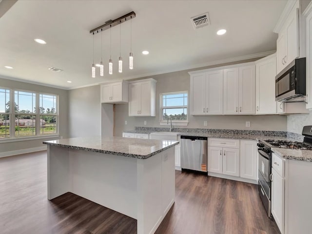 128 Stoney Rdg, Lufkin, TX 75904 - kitchen featuring appliances with stainless steel finishes, white cabinets, dark wood-type flooring, light stone counters, and ornamental molding