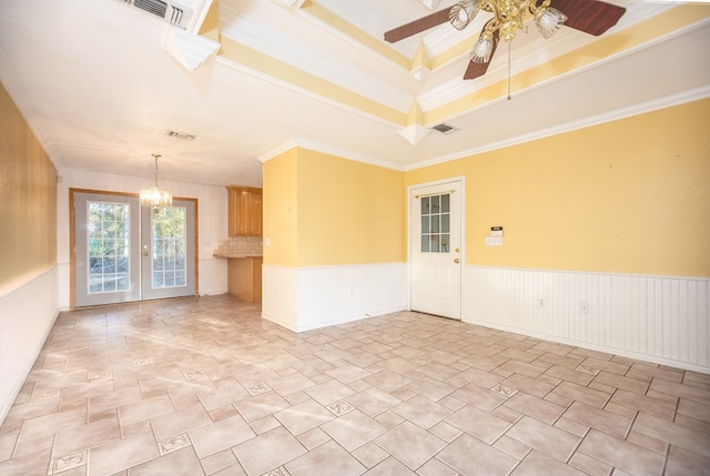 spare room featuring ceiling fan with notable chandelier, a raised ceiling, ornamental molding, and french doors