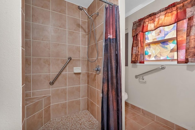 full bath with tile patterned flooring, ornamental molding, a tile shower, and toilet