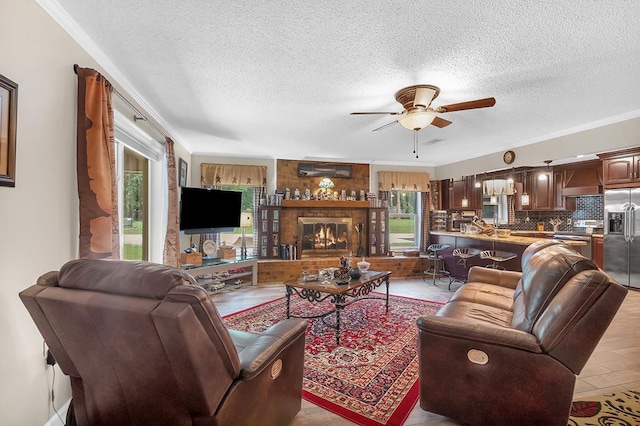 living room featuring a brick fireplace, crown molding, a textured ceiling, and ceiling fan