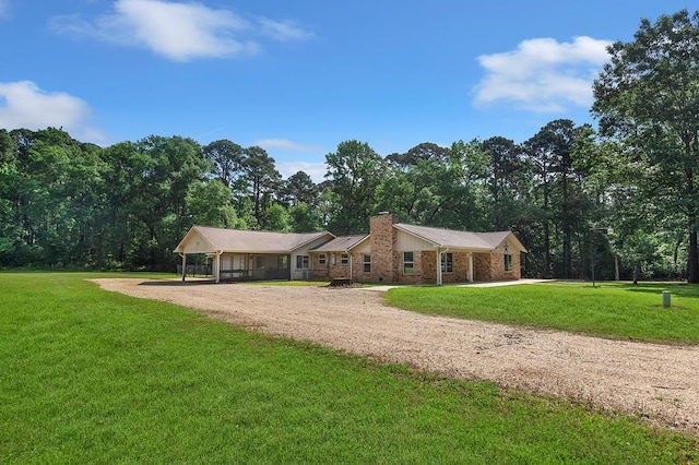 single story home featuring dirt driveway, a front yard, a chimney, and a carport