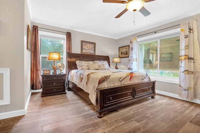 bedroom with baseboards, multiple windows, ornamental molding, and wood finished floors