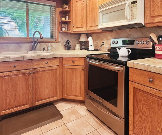 2104 Pinecrest Dr, Jasper, TX 75951 - kitchen featuring white microwave, electric range, light tile patterned flooring, and backsplash