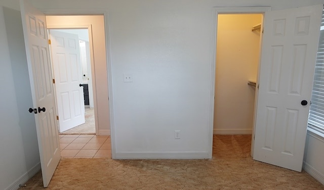 157 Sandalwood, Lufkin, TX 75904 - unfurnished bedroom featuring light colored carpet, a walk in closet, baseboards, a closet, and light tile patterned floors