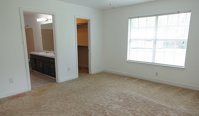 157 Sandalwood, Lufkin, TX 75904 - unfurnished bedroom featuring a walk in closet, a sink, light colored carpet, and multiple windows