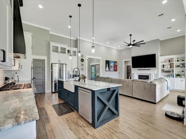 kitchen with a large island, sink, appliances with stainless steel finishes, hanging light fixtures, and white cabinets