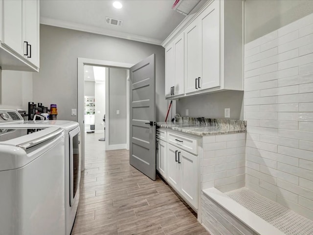 laundry room with cabinets, crown molding, and washer and clothes dryer