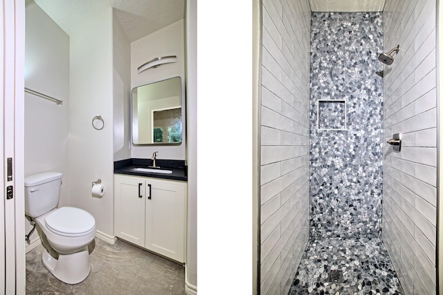 bathroom featuring toilet, vanity, and tiled shower