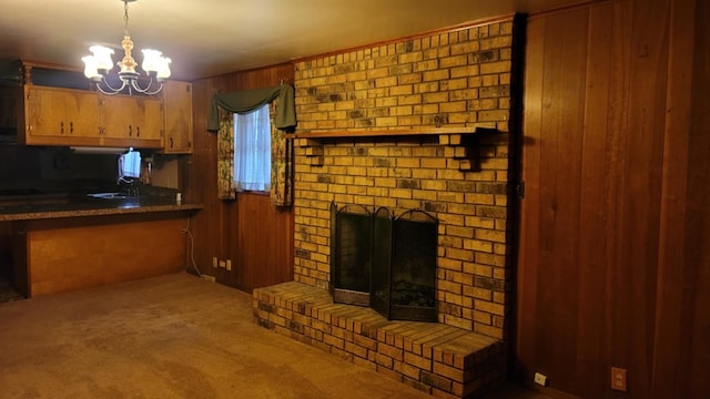 unfurnished living room featuring wood walls, a fireplace, light carpet, and an inviting chandelier