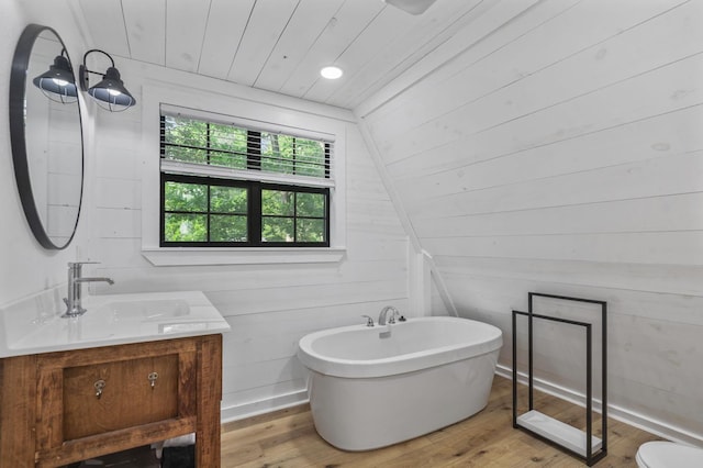 bathroom with hardwood / wood-style flooring, a bathing tub, lofted ceiling, and wooden walls