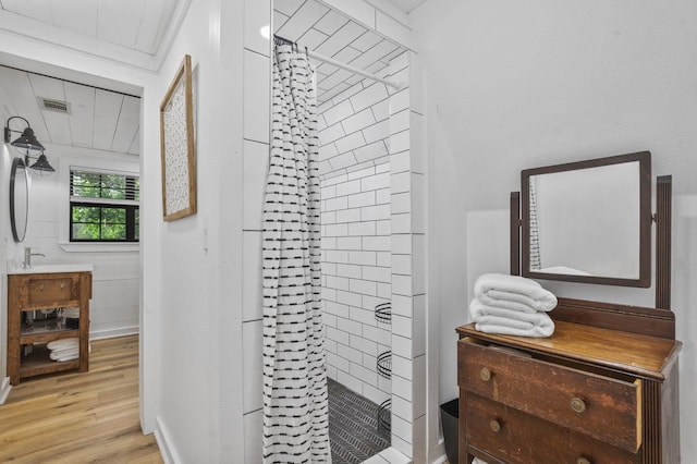 bathroom with hardwood / wood-style flooring, vanity, and tiled shower