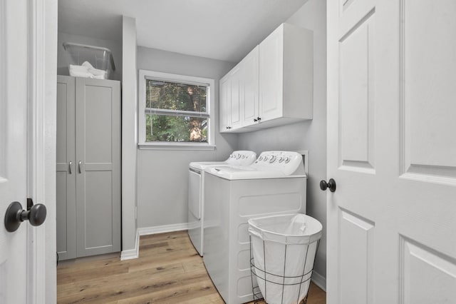 clothes washing area with light hardwood / wood-style floors, cabinets, and washing machine and clothes dryer