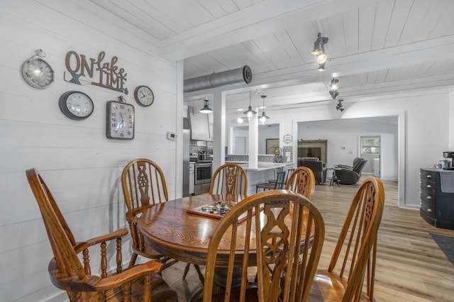 dining area with beam ceiling, light hardwood / wood-style floors, wood ceiling, and wood walls