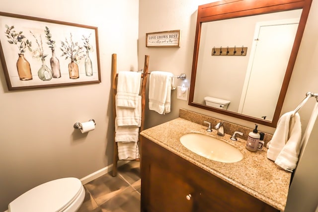 bathroom featuring toilet, vanity, and baseboards