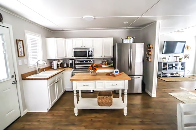 kitchen featuring a sink, dark wood finished floors, white cabinetry, stainless steel appliances, and butcher block counters