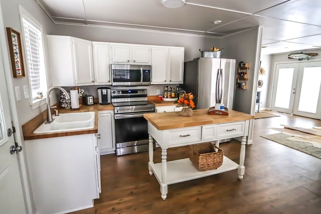 kitchen featuring a sink, wood counters, appliances with stainless steel finishes, white cabinets, and dark wood-style flooring
